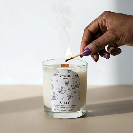Orchid scented candle Hand lighting a scented sea salt orchid candle.