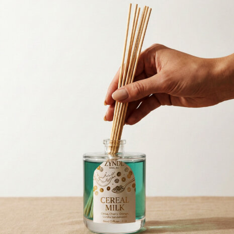 Hand placing reeds in diffuser bottle