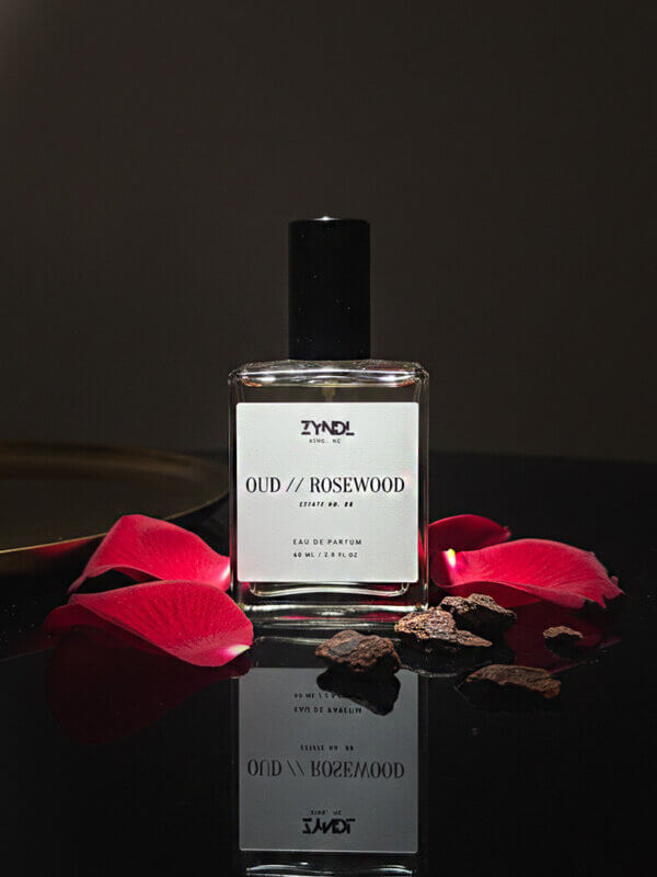 rosewood perfume bottle with rose petals.