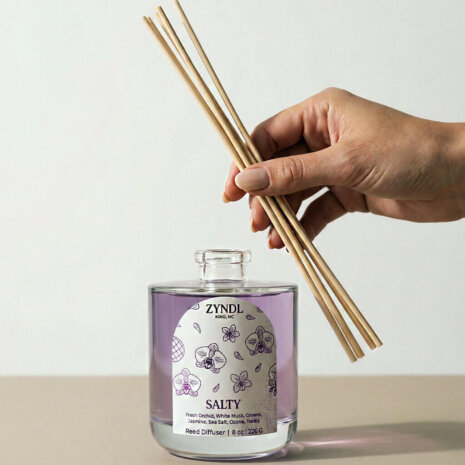 sea salt and orchid scent Hand holding sea salt and orchid scented reed diffuser